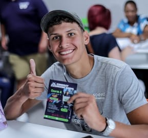 A happy student at Kimberley Driving School holding a flyer from Kimberley Driving School and showing a thumbs up at the camera