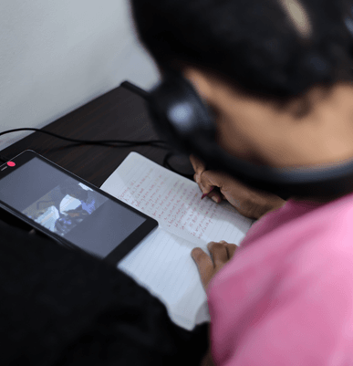 A student listening and taking notes of prerecorded lessons